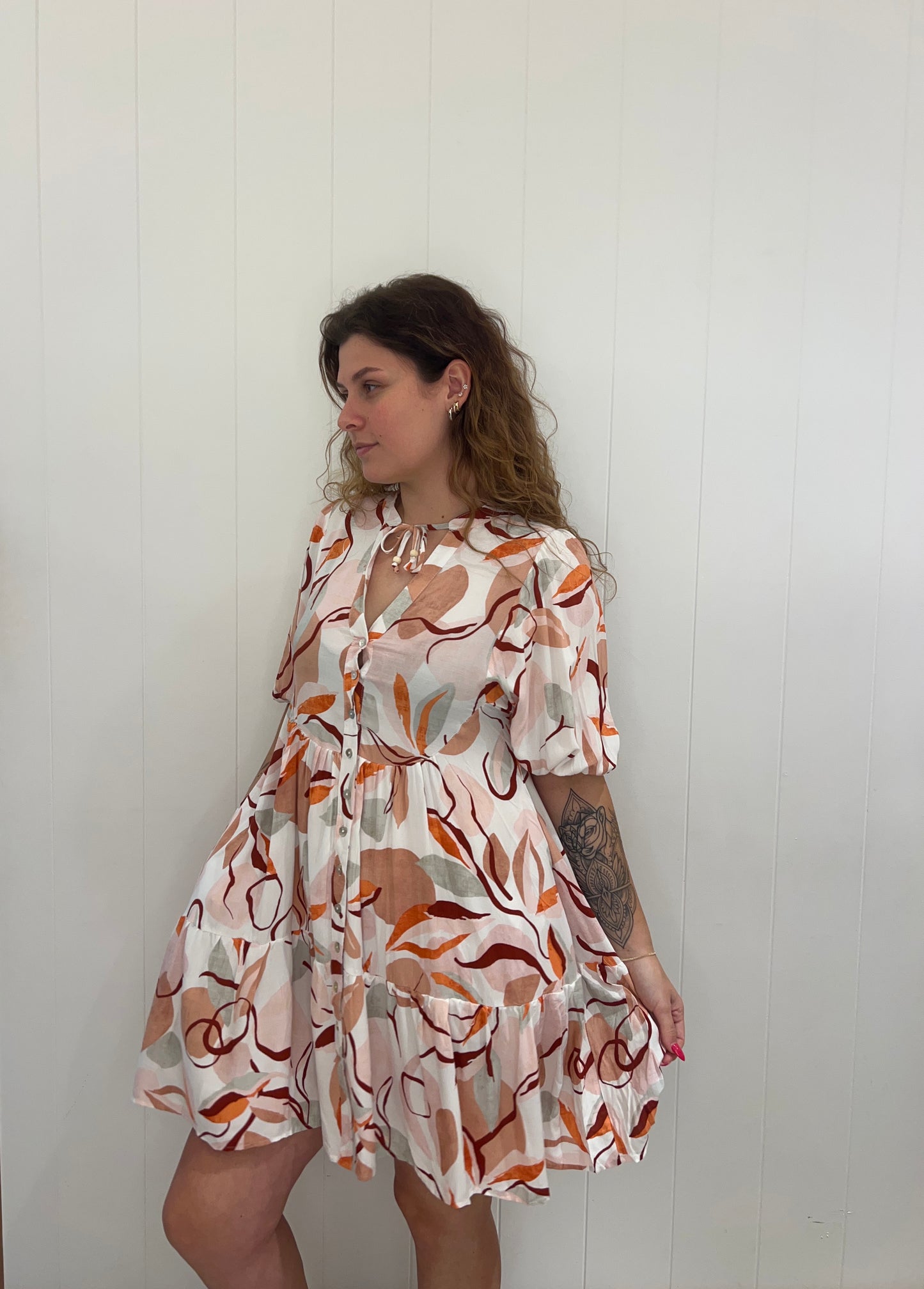 Experience the luxury of the Rosie Mini Dress. Crafted with elegant button details, a V-neckline, elasticated cuffs, and a tiered skirt, this dress provides a stunning and sophisticated look for any occasion.
