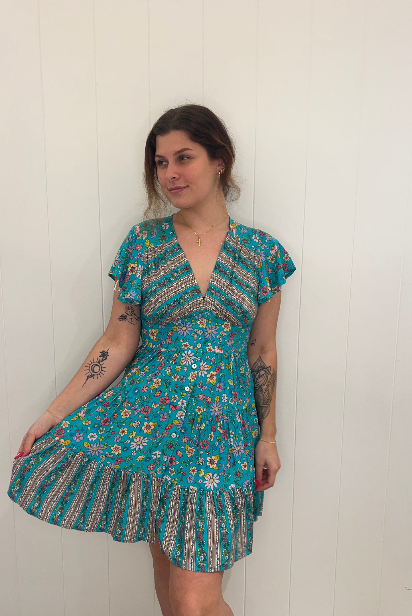 Introducing the Xoey Mini Dress, a flawless piece of sophistication and elegance. Crafted from soft fabric, the dress is designed with a v-neckline, delicate button detail, and an elasticated waist for subtle definition, while the tiered style and sweeping bell sleeves lend a romantic touch. Perfect for any special occasion.