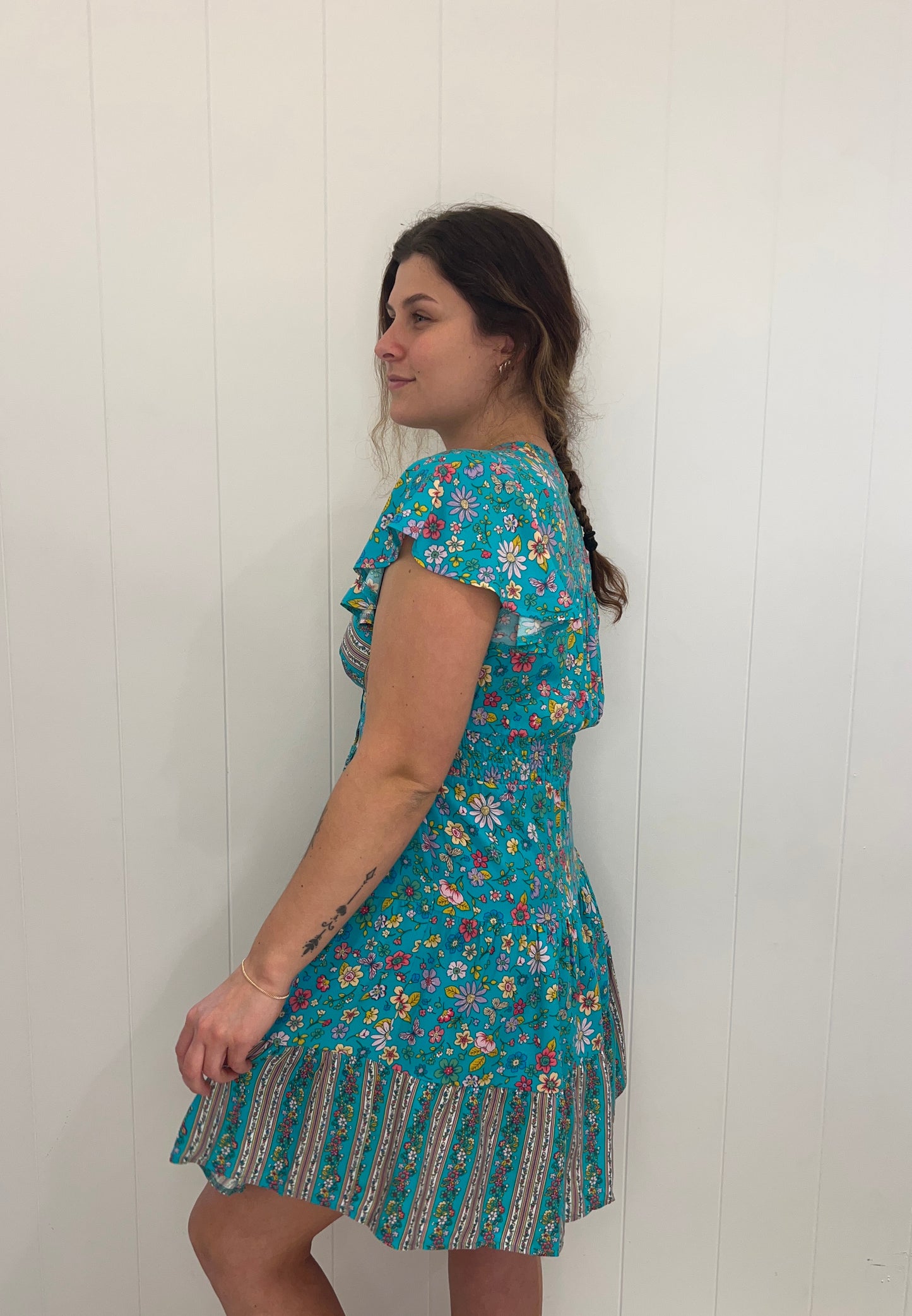 Introducing the Xoey Mini Dress, a flawless piece of sophistication and elegance. Crafted from soft fabric, the dress is designed with a v-neckline, delicate button detail, and an elasticated waist for subtle definition, while the tiered style and sweeping bell sleeves lend a romantic touch. Perfect for any special occasion.