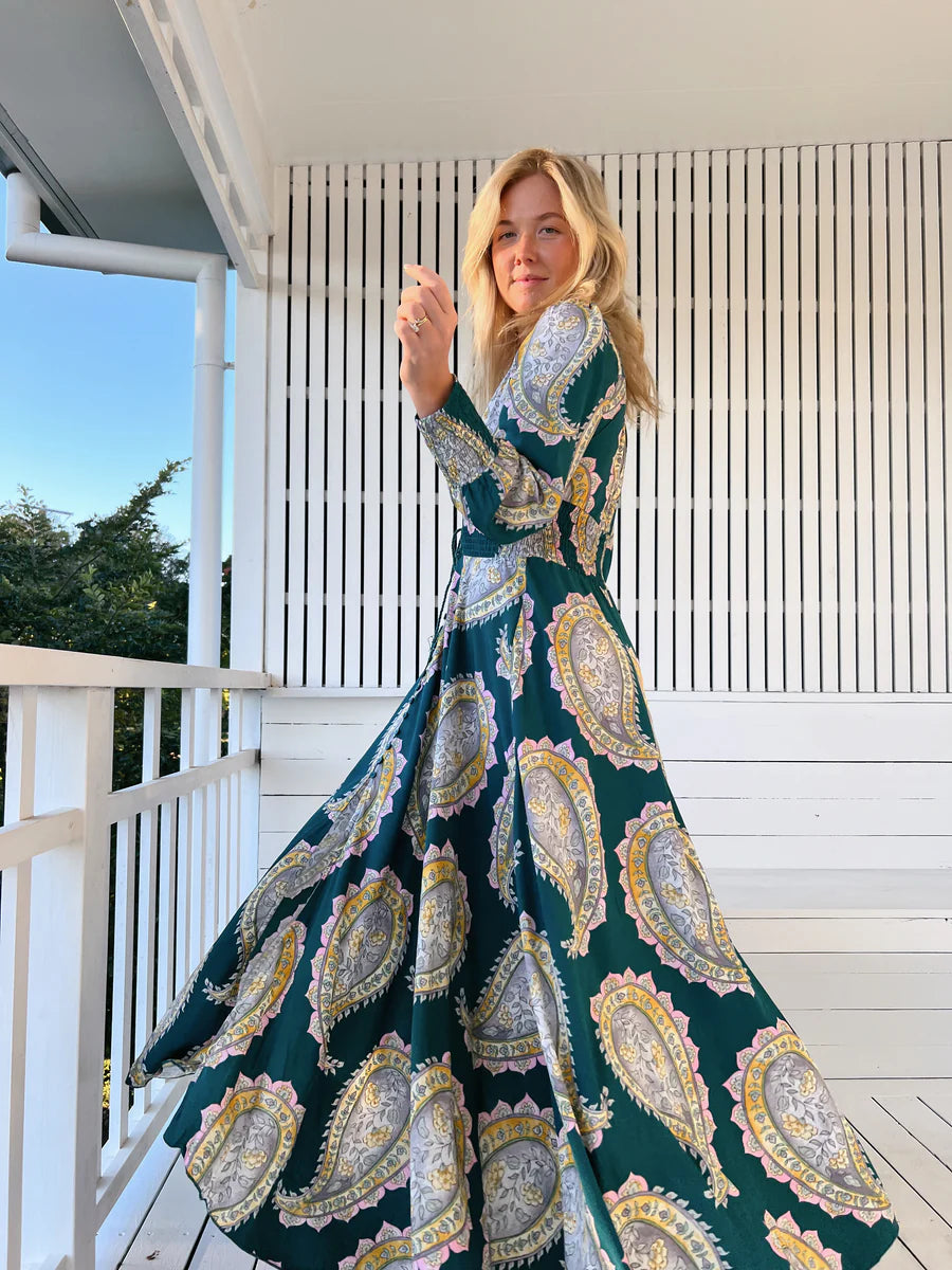 Unleash your free spirit with the Indie Maxi Mahala Print. This playful dress features a V neck line, button through design, and shirred cuffs for a bohemian vibe. The elastic waist ensures a comfortable and flattering fit. Embrace your inner quirkiness and stand out in this one-of-a-kind piece!