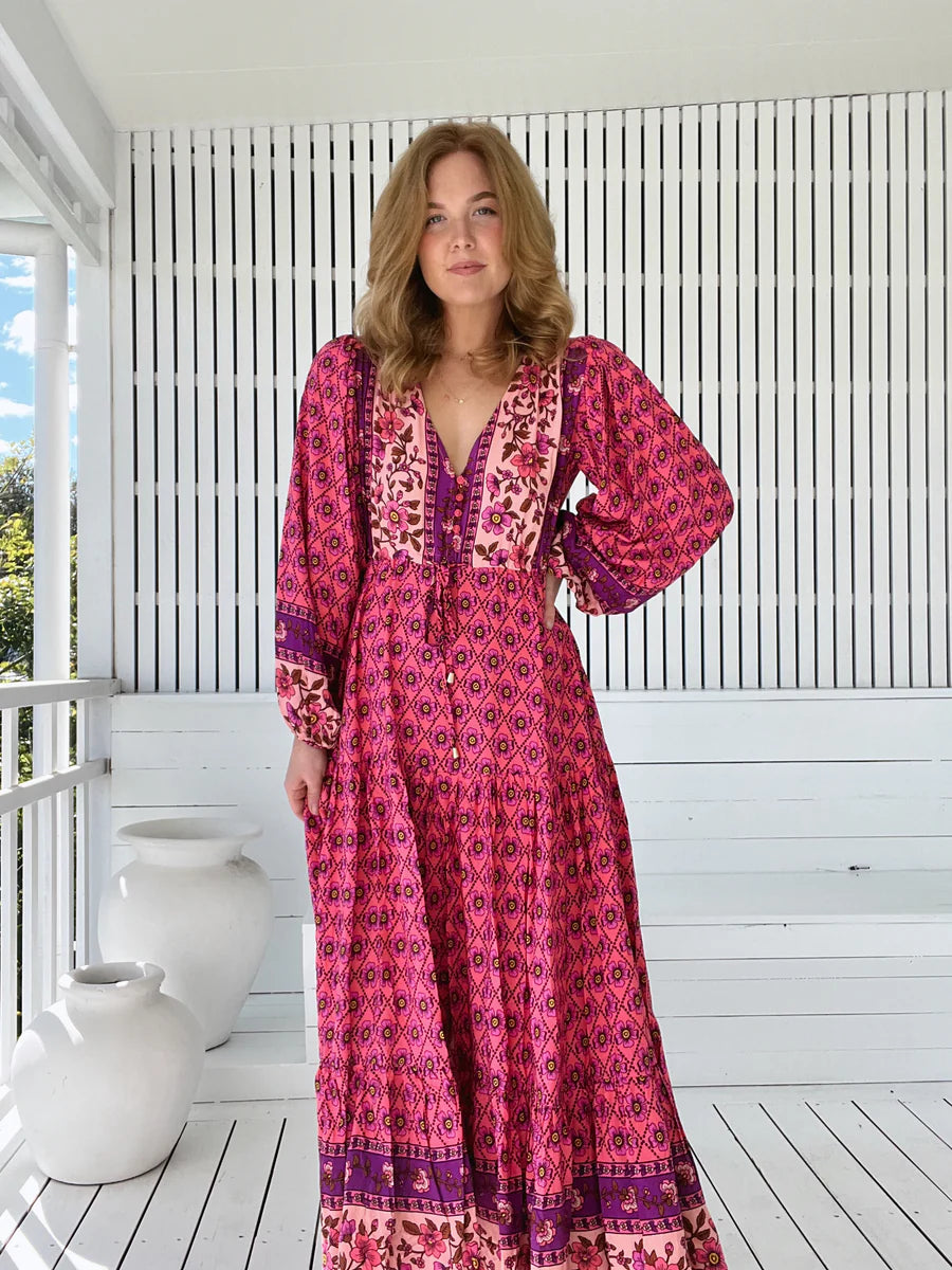 Unleash your inner boho babe with the Teresa Maxi dress in the captivating Jolene Print. The V neck-line and buttons down the bust add flirty details while the long billowy sleeves with cuffs add a touch of romance. Cinch your waist with the tie up feature for a figure-flattering silhouette.