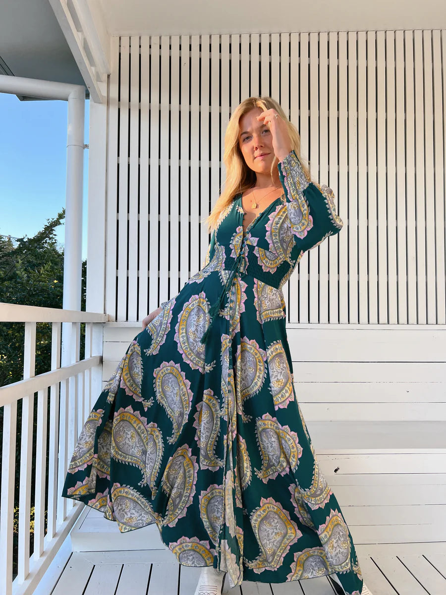 Unleash your free spirit with the Indie Maxi Mahala Print. This playful dress features a V neck line, button through design, and shirred cuffs for a bohemian vibe. The elastic waist ensures a comfortable and flattering fit. Embrace your inner quirkiness and stand out in this one-of-a-kind piece!