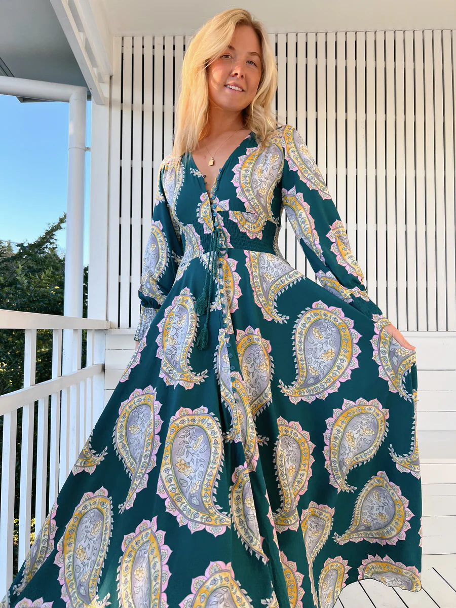 Unleash your free spirit with the Indie Maxi Mahala Print. This playful dress features a V neck line, button through design, and shirred cuffs for a bohemian vibe. The elastic waist ensures a comfortable and flattering fit. Embrace your inner quirkiness and stand out in this one-of-a-kind piece!