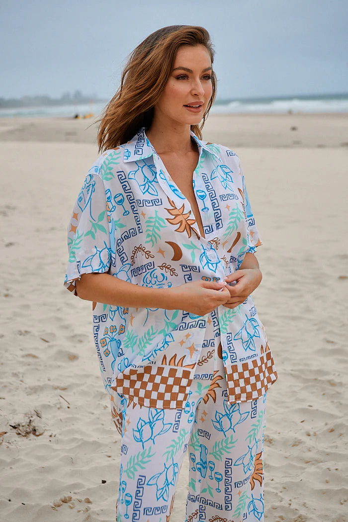 Introducing Lola - Rhodes Shirt! This stylish and playful shirt features a folded collar, V-neckline, and 1/2 sleeves with folded cuffs. The buttoned down front adds a touch of sophistication, while the scooped high-low hemline adds a unique twist.