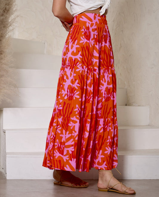 Person wearing a vibrant orange and pink patterned skirt standing on a staircase.