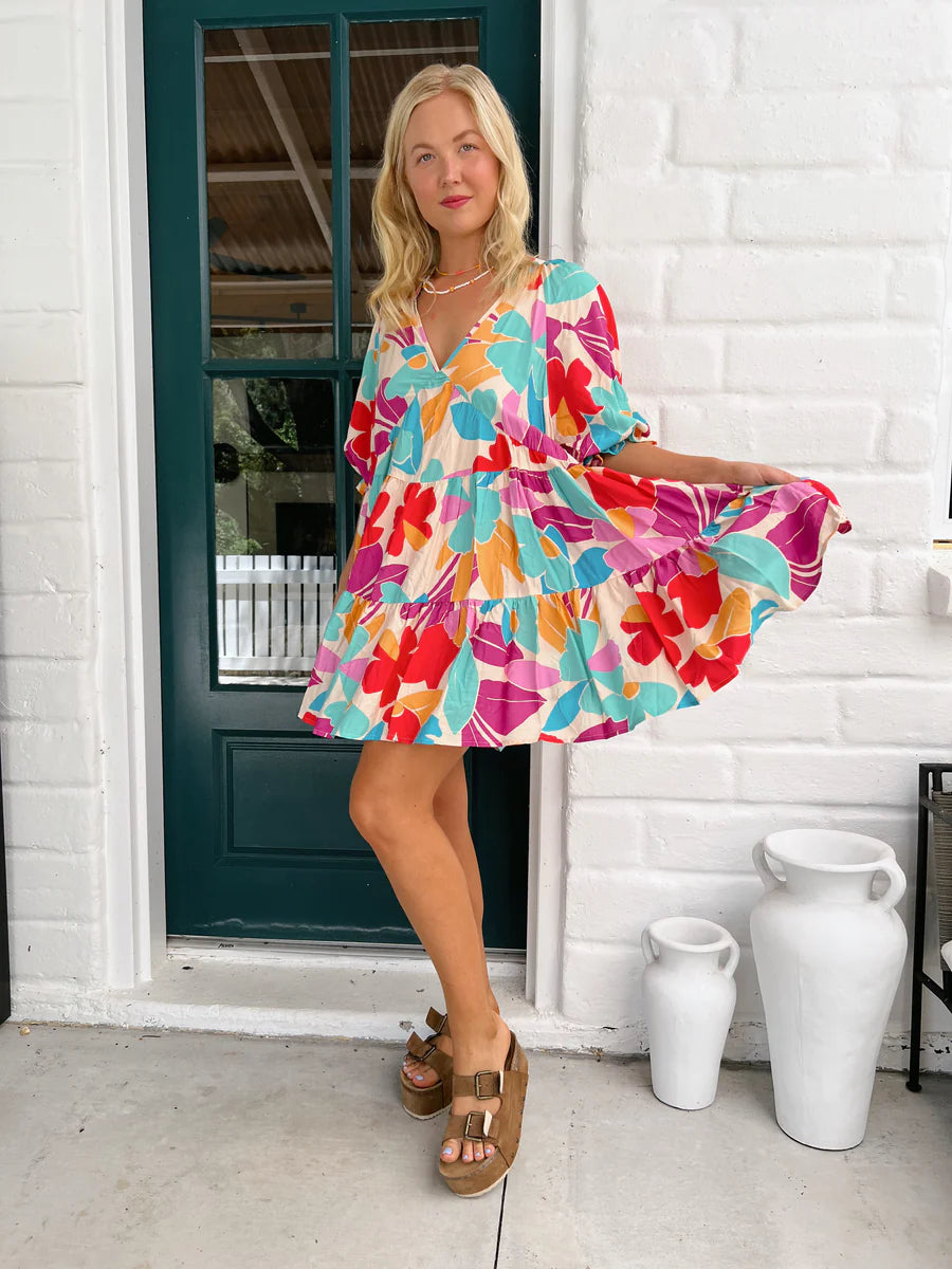 This striking Petal Mini Dress boasts an Ohana Print and a playful V Neckline. The tiered style and elasticated cuff sleeves add a touch of whimsy to this must-have piece. Perfect for a fun and carefree day out, this dress will have you feeling like the life of the party!