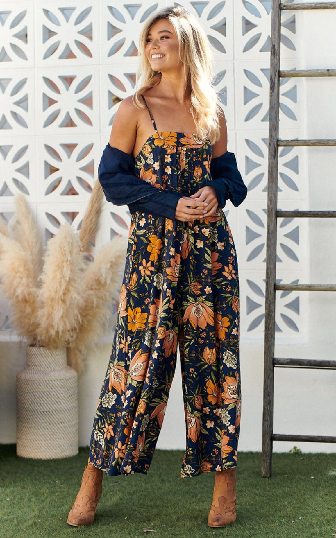 Elevate your style with the Florida Jumpsuit in Navy California Poppy. Featuring elegant pleated details and delicate shoestring straps, this jumpsuit exudes sophistication. Designed with a cropped ankle length and wide leg pants, it's perfect for any occasion. Indulge in luxury with this exclusive piece.